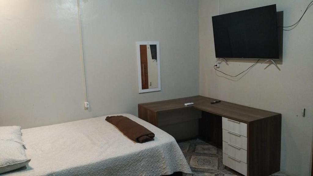 马卡帕AP 4 - Apartamento Espaçoso, Confortável e Aconchegante - Pousada Paraíso的一间卧室配有一张床、一张书桌和一台电视