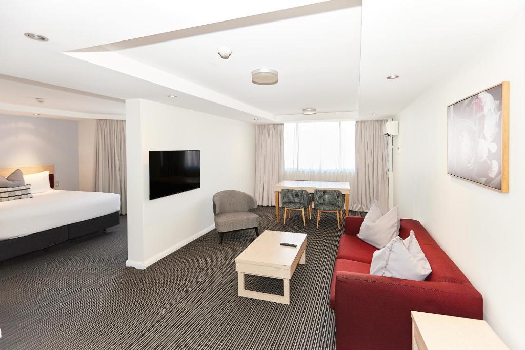 悉尼Central Studio Hotel Sydney的酒店客房,配有一张床和一张红色的沙发