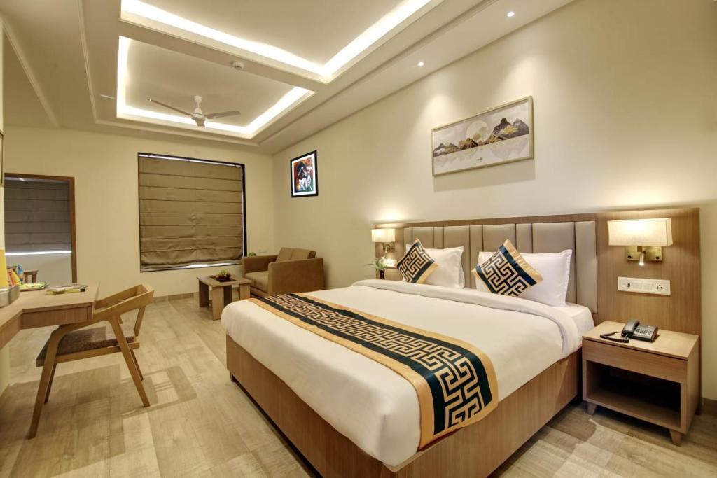 新德里Hotel King Plaza的酒店客房设有一张大床和一张书桌。
