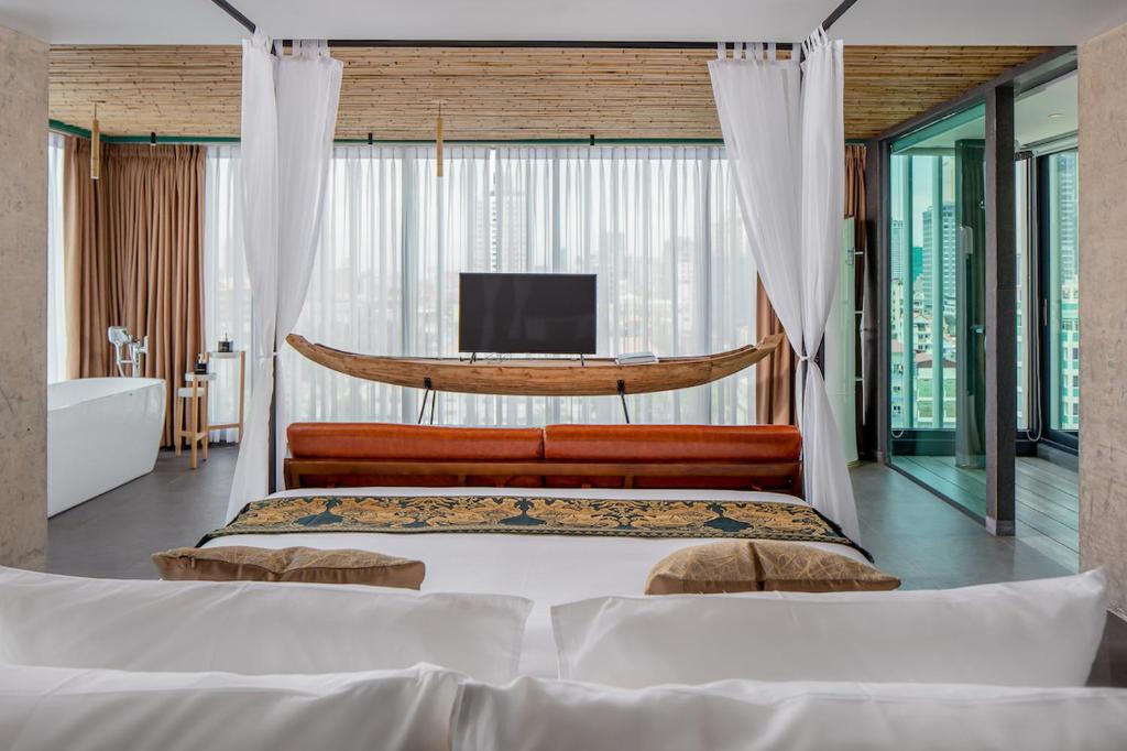 金边CHECK inn Phnom Penh Royal Palace的一间卧室配有一张床、一个浴缸和一台电视。