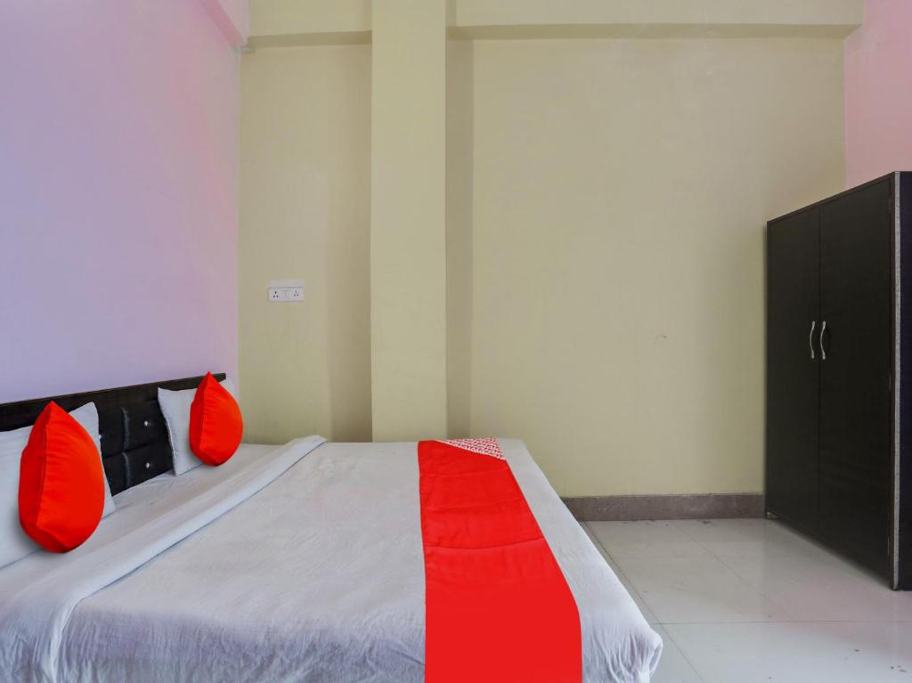 坎普尔OYO Flagship Radhe Radhe Hotels的一间卧室配有一张带红色枕头的床和橱柜。