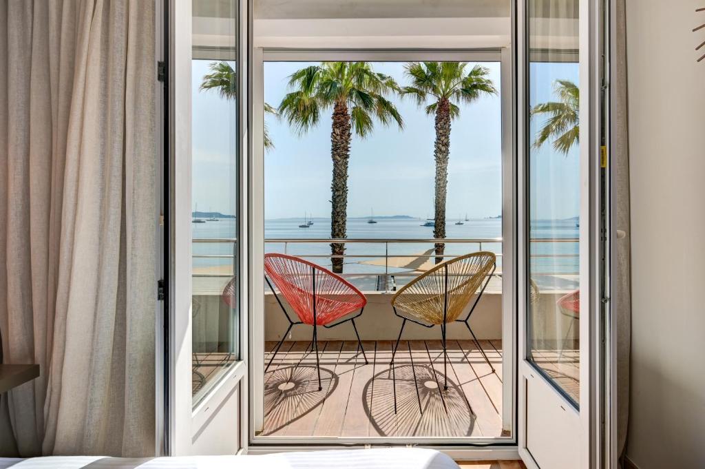 耶尔Hôtel Bor的两把椅子坐在棕榈树阳台