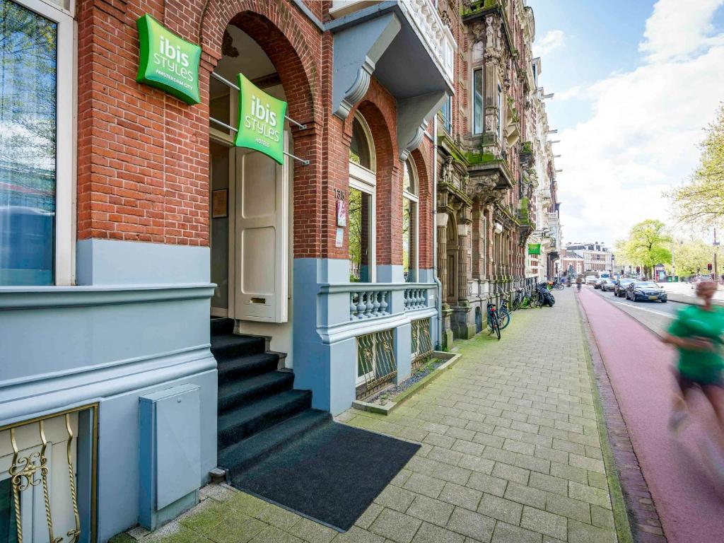 阿姆斯特丹全季 - 雅高酒店的走在建筑物前的街道上的女人