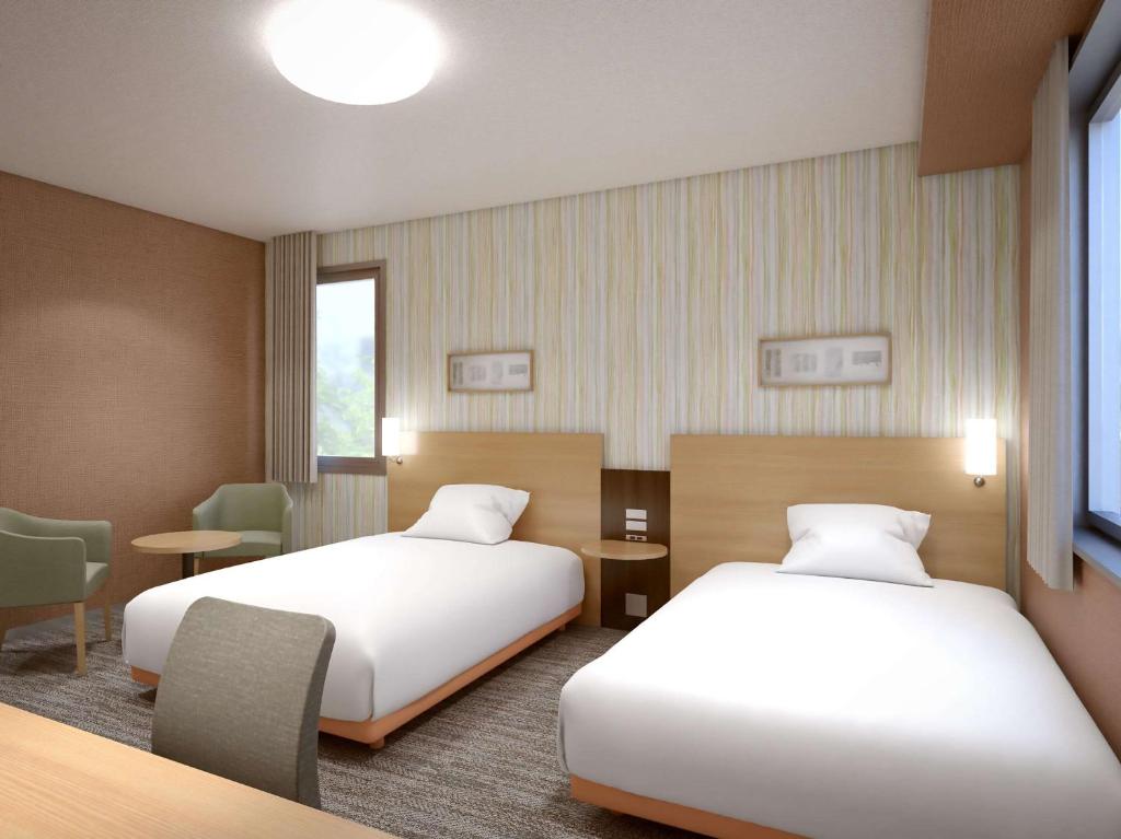 前桥市前桥舒适酒店的酒店客房设有两张床和一张桌子。