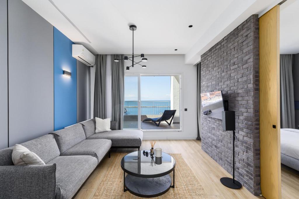 塞萨洛尼基#Oddity seafront apartments的客厅设有灰色的沙发和砖墙