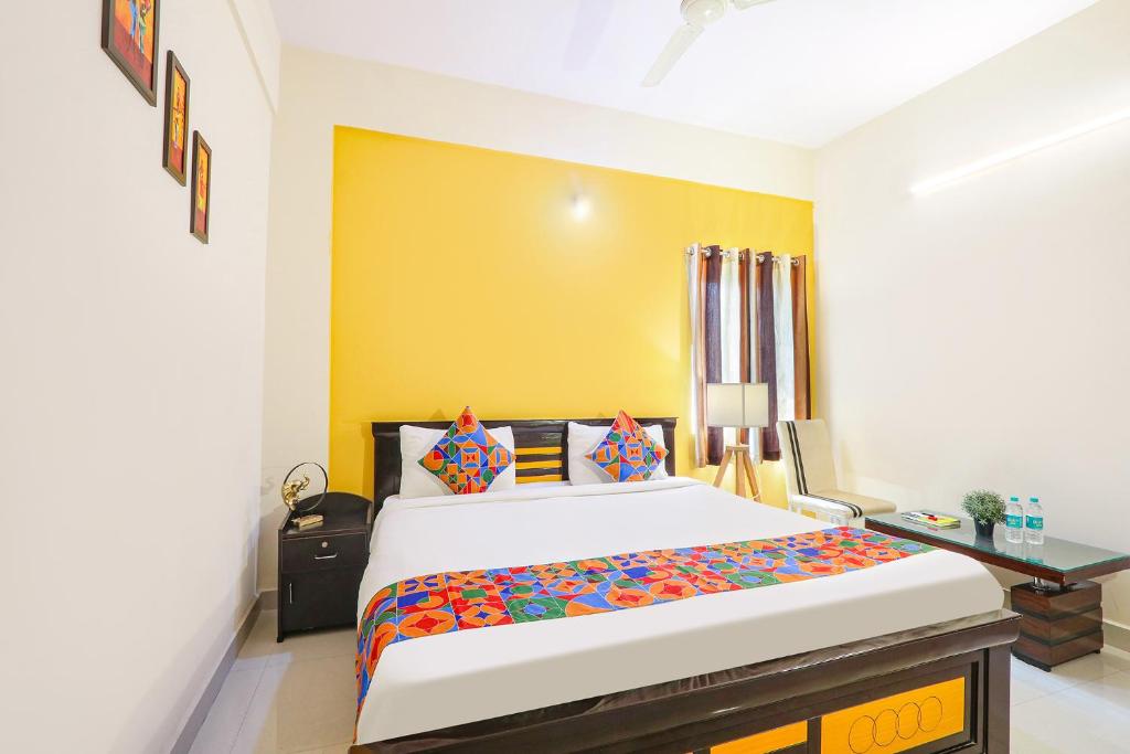 海得拉巴FabHotel Namaha Suites的一间卧室配有一张床和一张书桌,墙壁为黄色