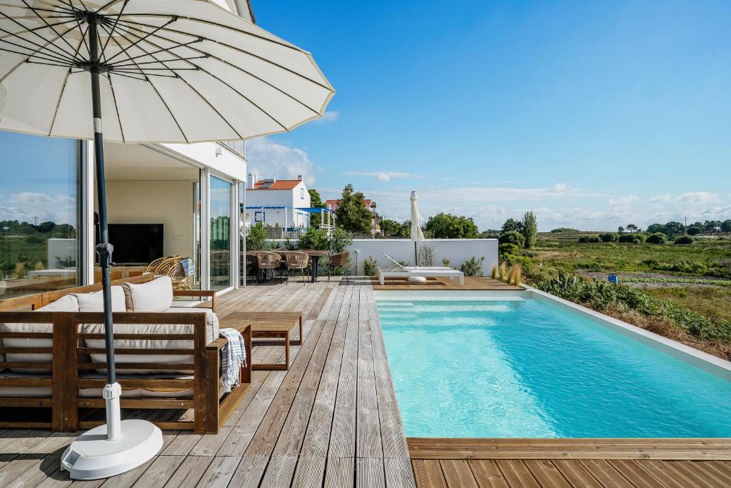 孔波尔塔Villa Possanco, Comporta beach villa的一座带游泳池和遮阳伞的房子