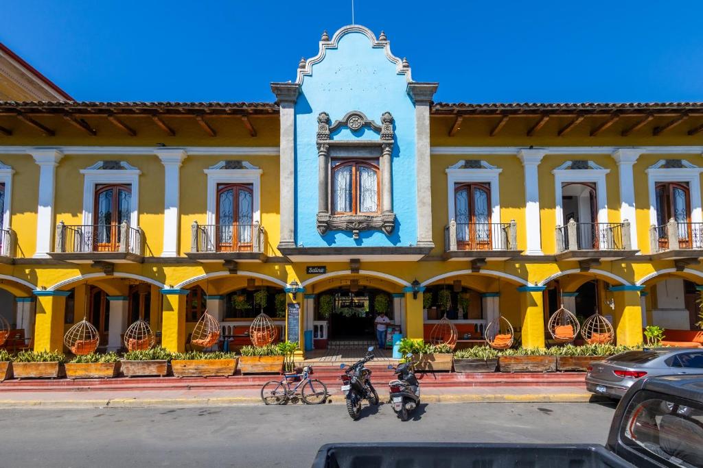 格拉纳达Selina Granada的一座黄色的建筑,前面有自行车停放