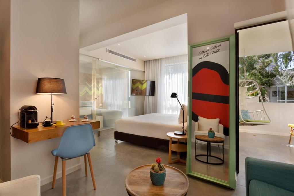 特拉维夫Cucu Hotel By 7Minds的酒店客房带一张床、一张桌子和椅子