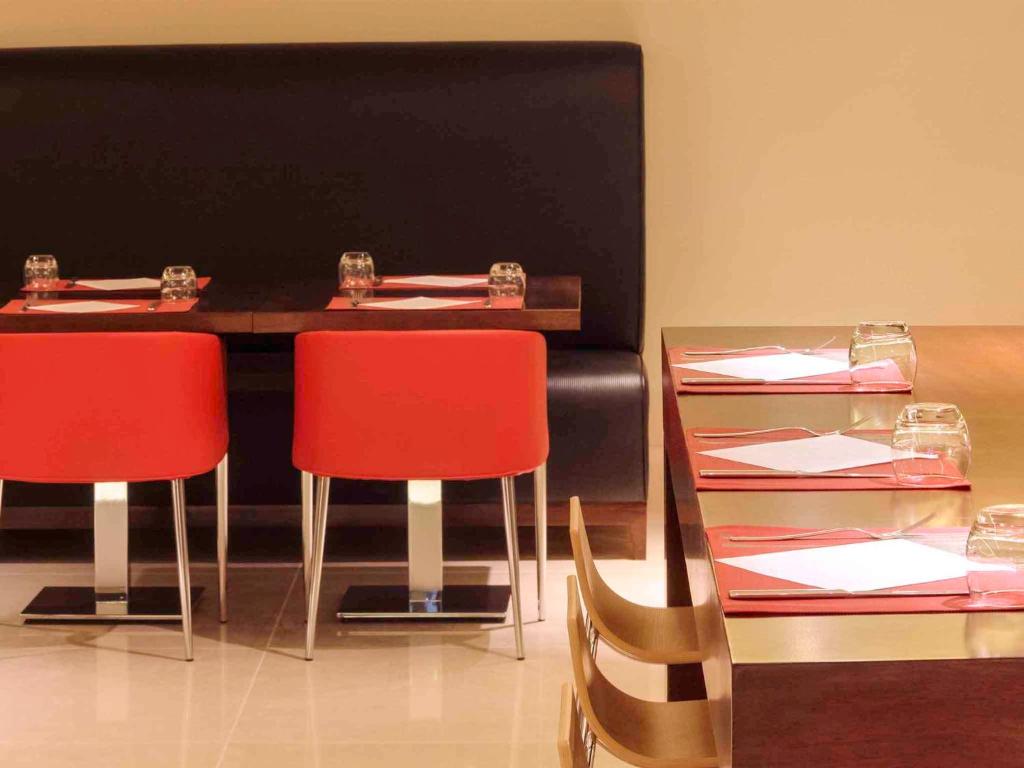 利雅德利雅得奥拉亚街宜必思酒店的一间设有两张桌子和红色椅子的用餐室