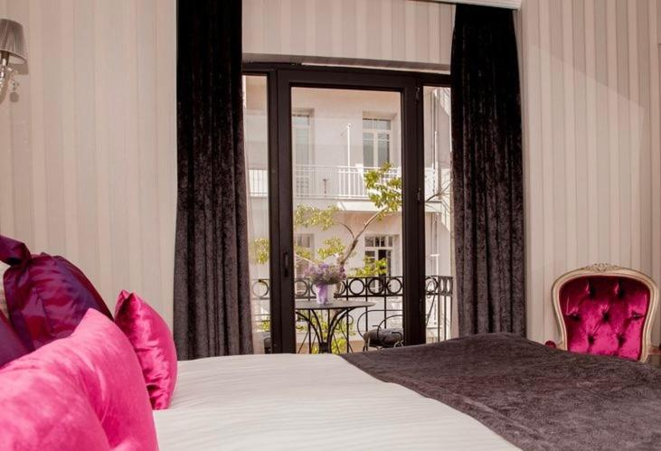 伊斯坦布尔In Pera Boutique Hotel的一间卧室配有带粉红色枕头的床和阳台