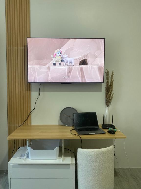 马尼拉Cozy & Minimalist Room at Amaia Steps Alabang的挂在桌子上方的墙上的电视,带笔记本电脑