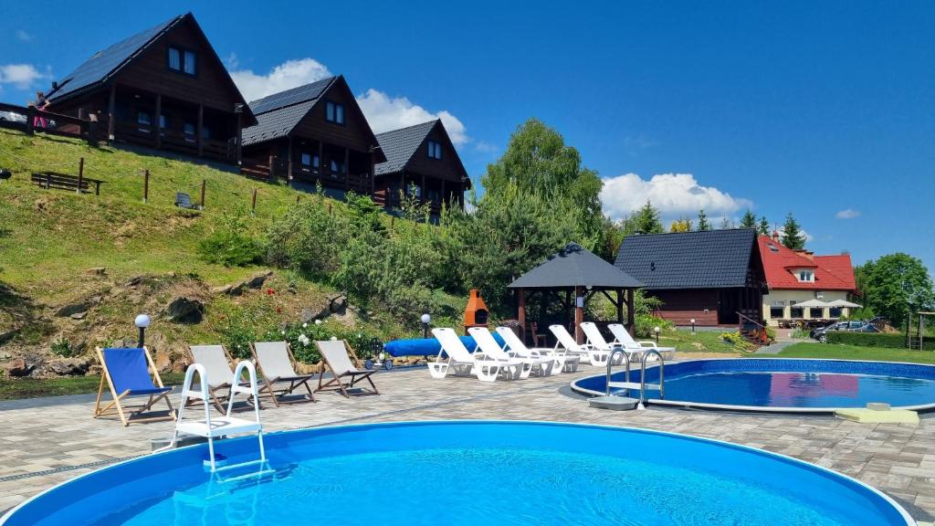 波拉齐克Na Górce - Domki z Widokiem Na Jezioro i Góry的一个带椅子的游泳池和一个背景房子