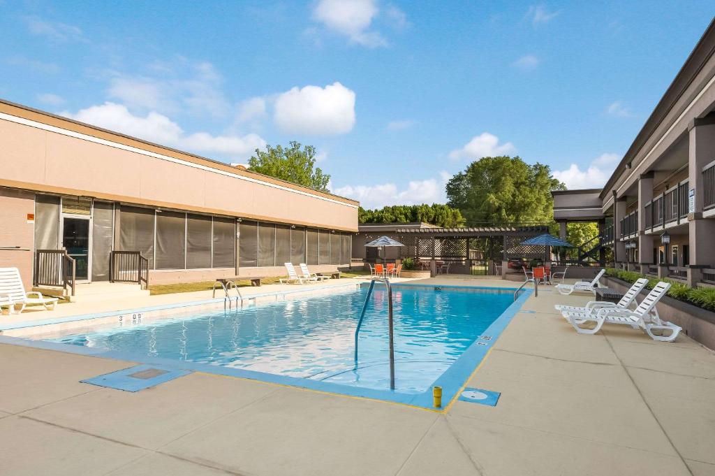 拉塞尔维尔Clarion Inn & Suites Russellville I-40的一座带两把椅子的游泳池以及一座建筑