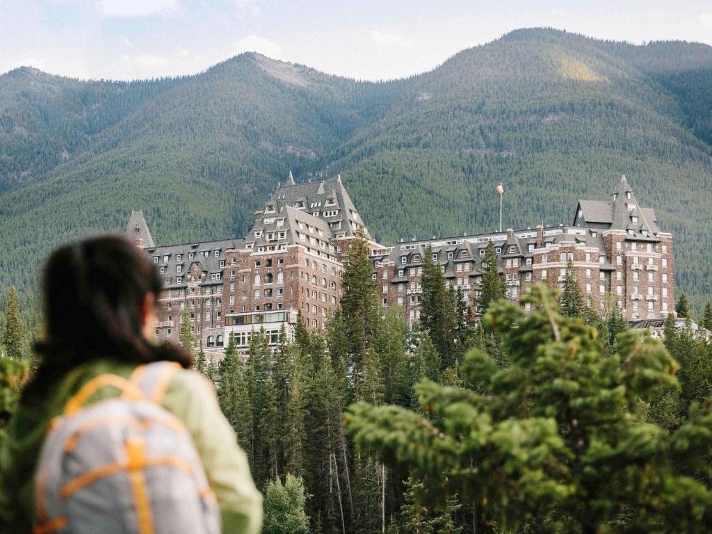 班夫费尔蒙班夫温泉酒店的一位背着背包的女人,看着山上的一座建筑