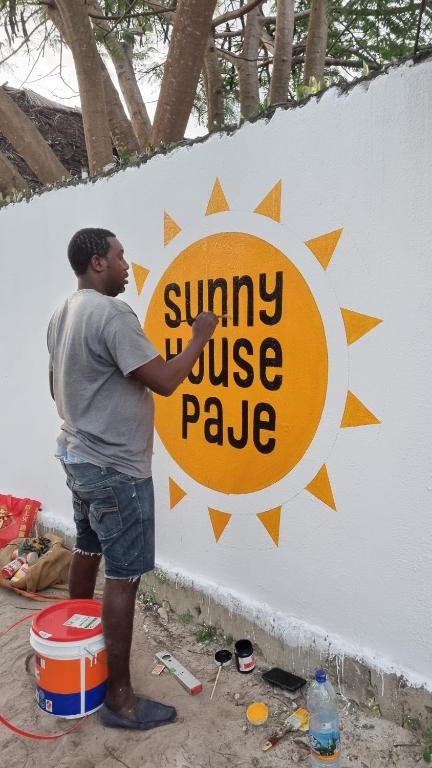 帕杰Sunny House Paje的站在墙上标志旁的人