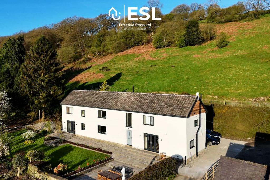 MinsterleyLarge Country Farmhouse with Hot Tub and Shropshire Hills View的山丘上白色房子的空中景色