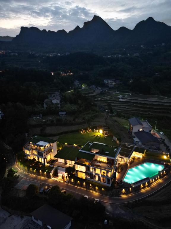 张家界XMAN Valley Sunrise Resort的享有度假村的空中景色,晚上设有游泳池