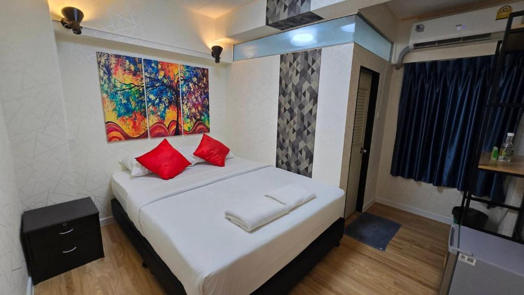 曼谷Khaosan Art Hotel - SHA Plus Certified的一间卧室配有一张带红色枕头的床和一幅画