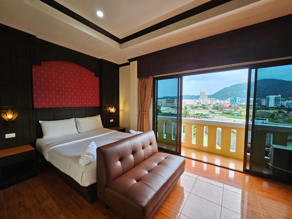 芭东海滩Nanai 2 Residence Patong Phuket的一间卧室配有一张床、一张沙发和一个大窗户