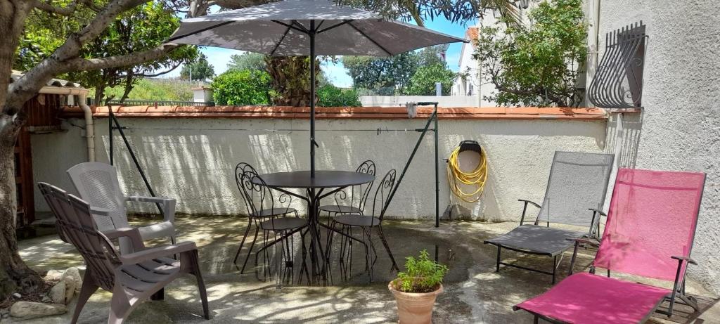 滨海阿热莱斯Charmant appartement de vacances的庭院配有桌椅和遮阳伞。