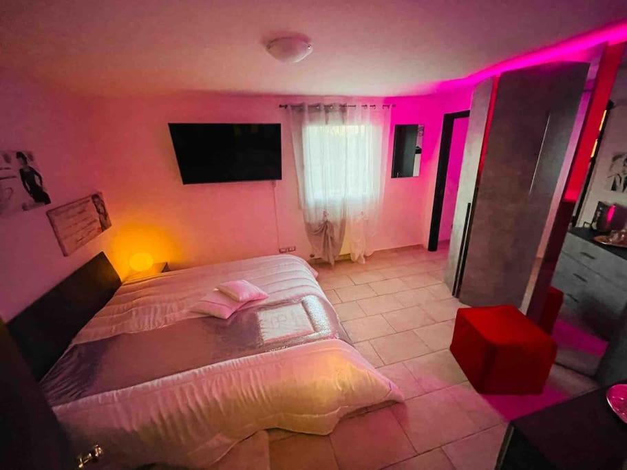 Appartamento a Udine con doccia idromassaggio的一间卧室配有一张带粉红色照明的大床