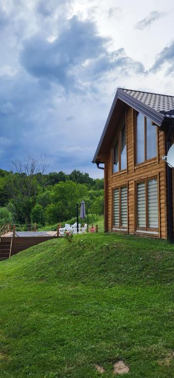 巴尼亚卢卡Vikendica Brvnara Marčetić的一座位于草木山丘上的木屋,毗邻一座房子