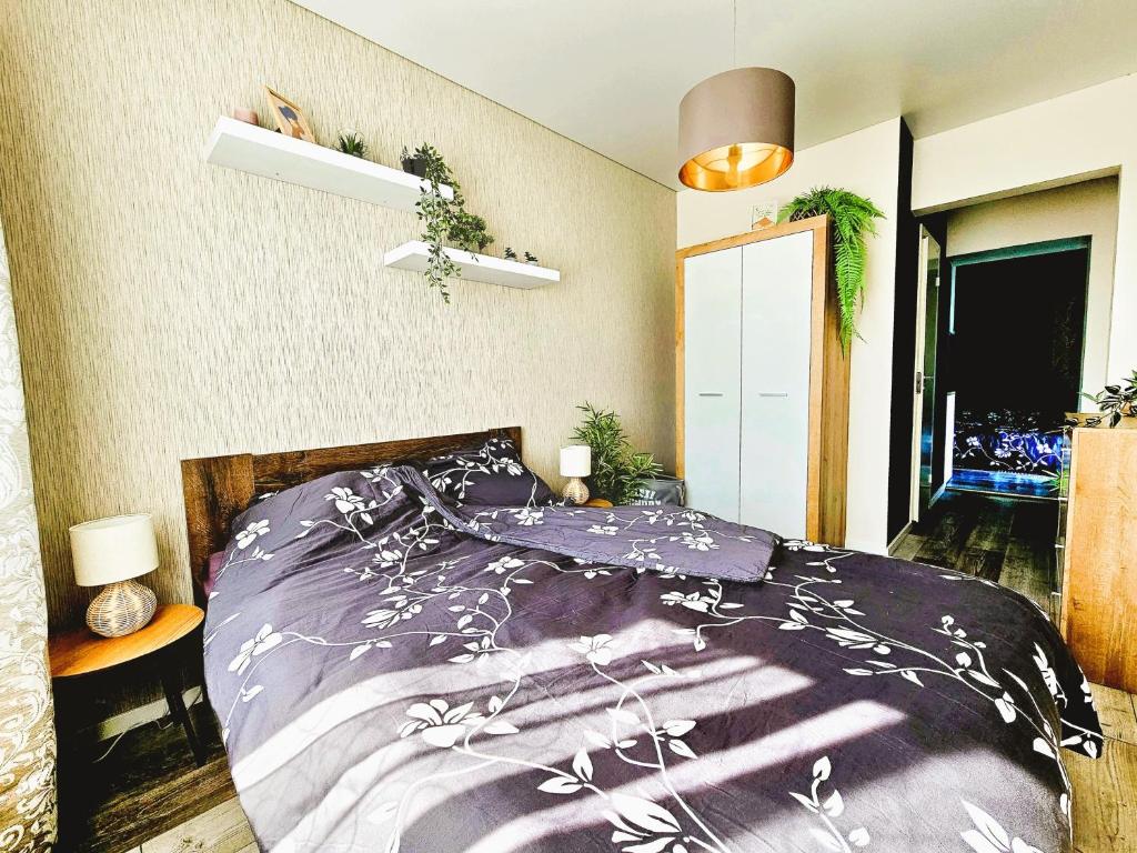 塔尔图Cofy Rentals - near-centrally located, quiet district, air-conditioning, free parking, 24-7 express check-in-out, close to nature, everything you need for living!的一间卧室配有一张带紫色棉被的床