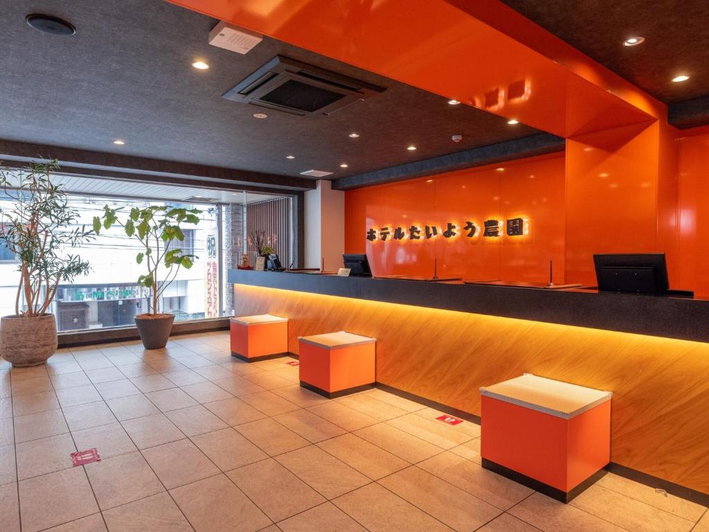 松山Hotel Taiyo Noen Nibancho的大堂设有橙色墙壁和带凳子的酒吧