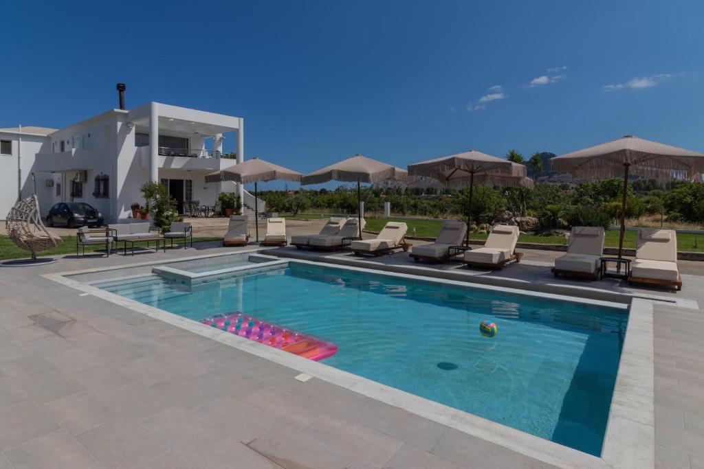 科林比亚Villa Nikoli的房屋前的游泳池配有椅子和遮阳伞