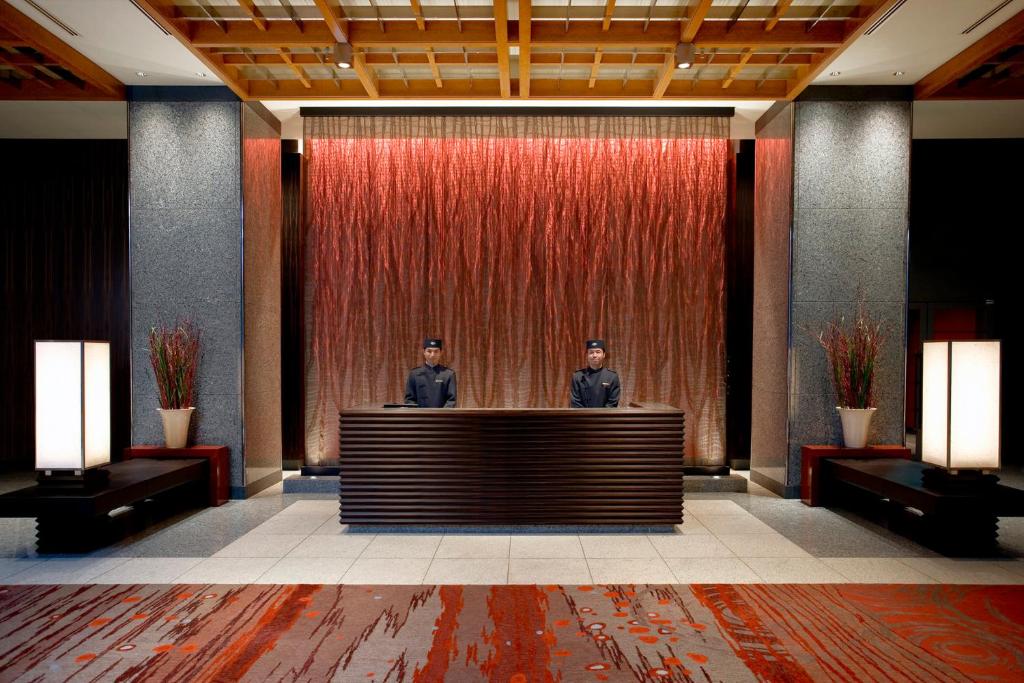 东京Mandarin Oriental, Tokyo的两个男人站在大堂的前台后面