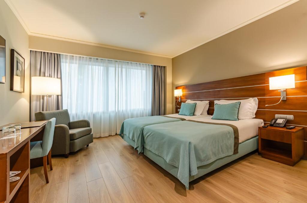 里斯本图林木欧罗巴酒店的配有一张床和一把椅子的酒店客房