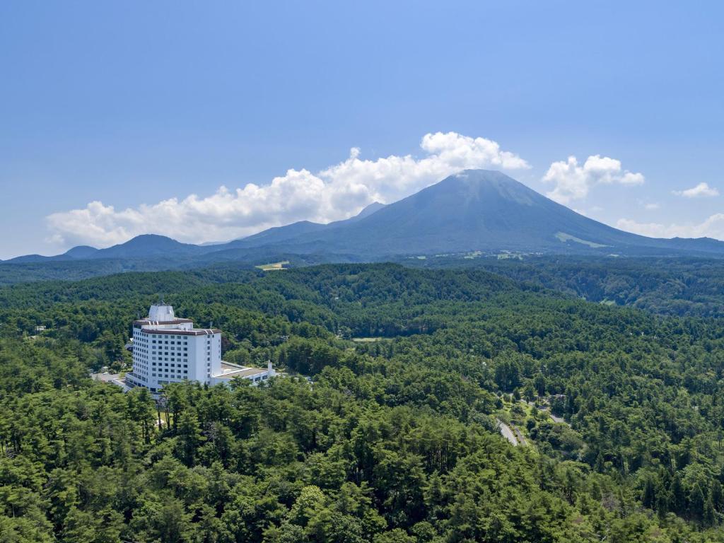 大山Mercure Tottori Daisen Resort & Spa的树上的建筑,背景是山