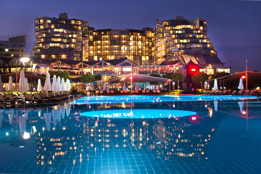 拉瑞Limak Lara Deluxe Hotel & Resort Antalya的一座大型游泳池,其建筑背景为: