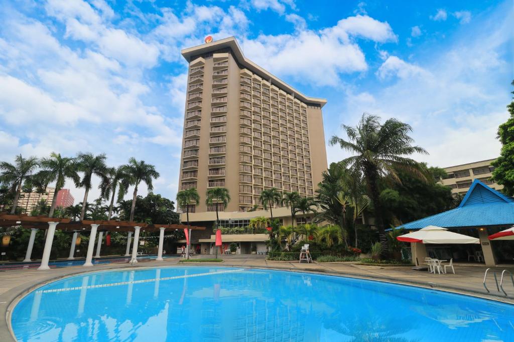 马尼拉Century Park Hotel的大型酒店前方设有大型游泳池