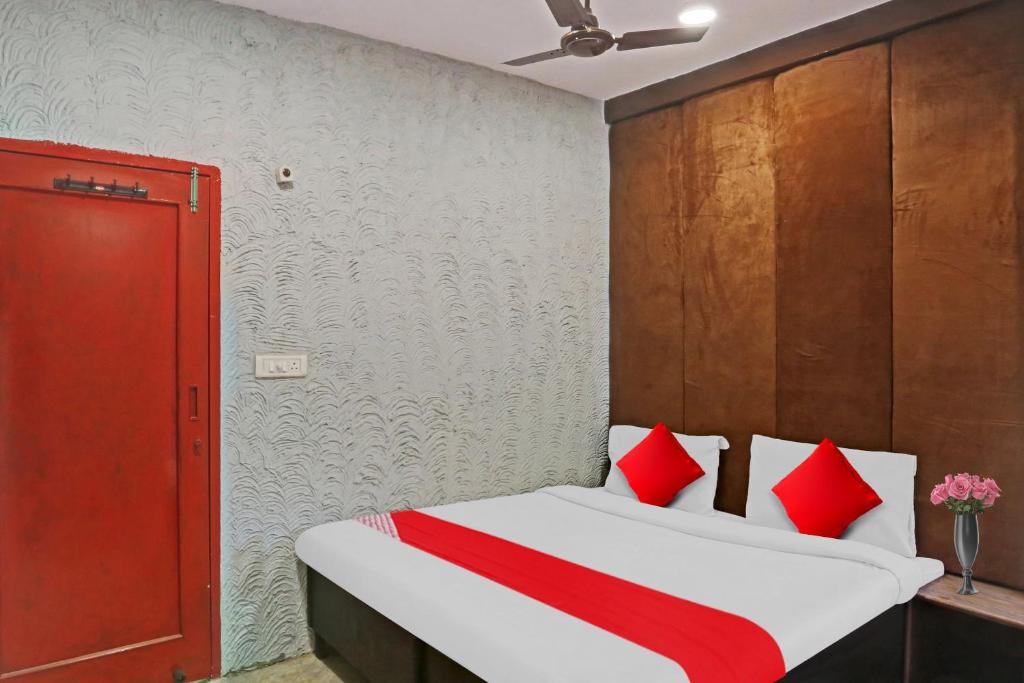 新德里Flagship Kashish Residency的一间卧室配有红色和白色枕头的床