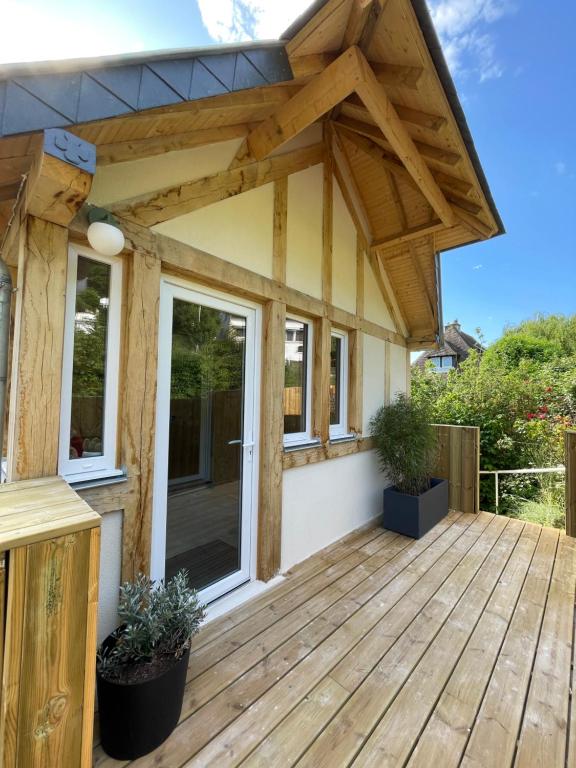 多维尔La cabine de Deauville的房屋设有遮阳篷的木制甲板