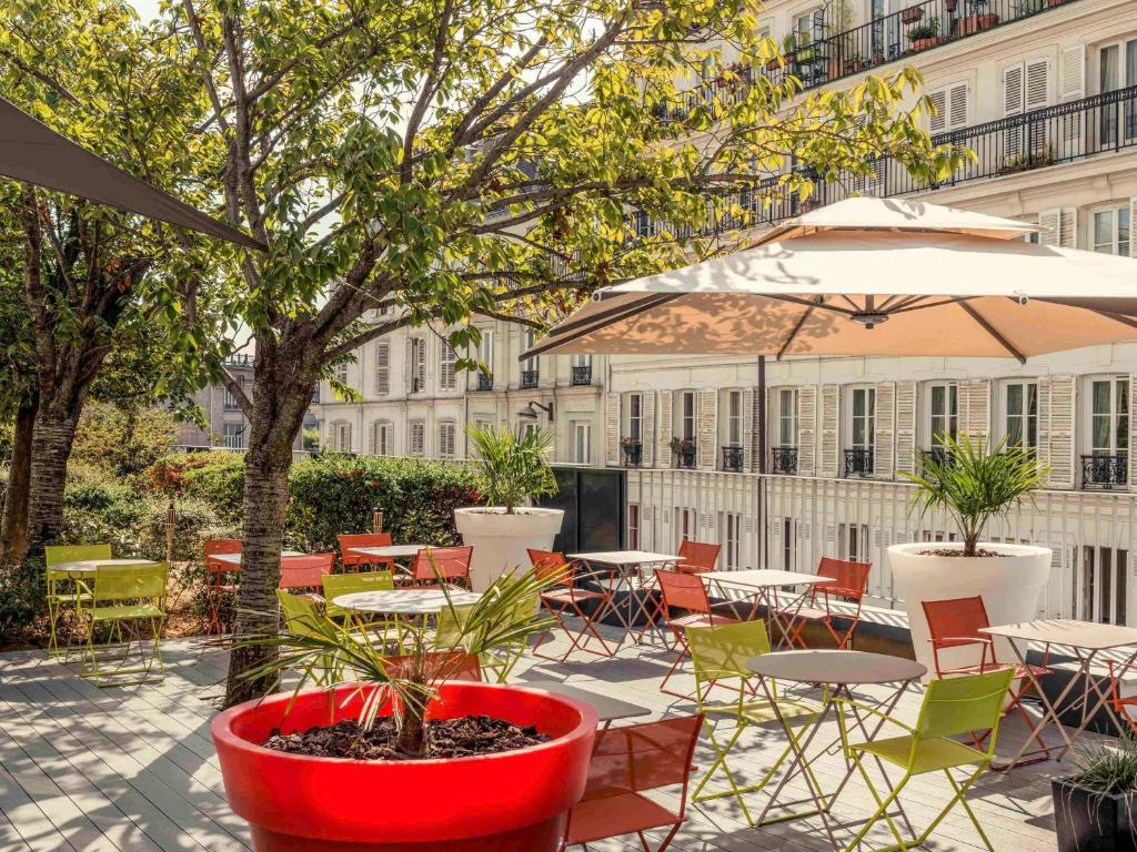 巴黎巴黎蒙马特圣心大教堂美居酒店的一个带桌椅和遮阳伞的庭院