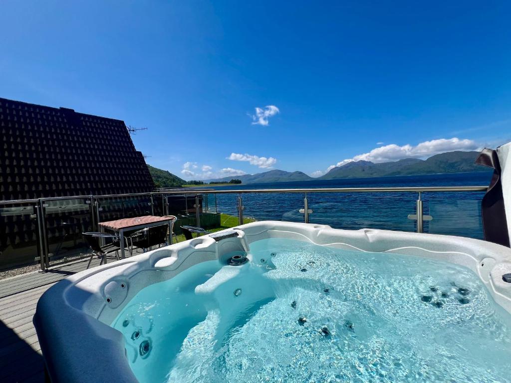 格伦科Loch Linnhe Waterfront Lodges with Hot Tubs的享有水景的按摩浴缸