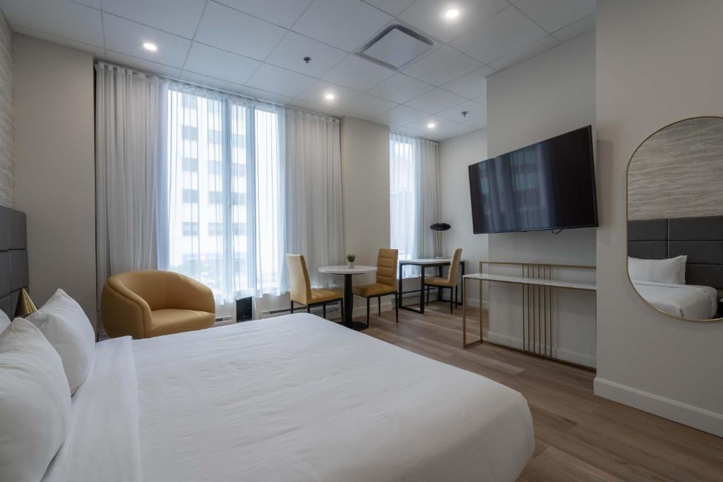 蒙特利尔蒙特利尔市中心旅客之家酒店的酒店客房设有白色的床和电视。