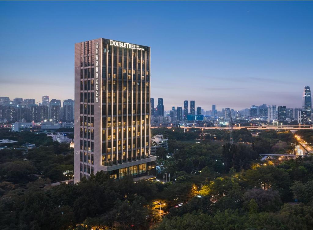 深圳深圳南山希尔顿逸林酒店及公寓的一座高大的建筑,城市里灯火通明