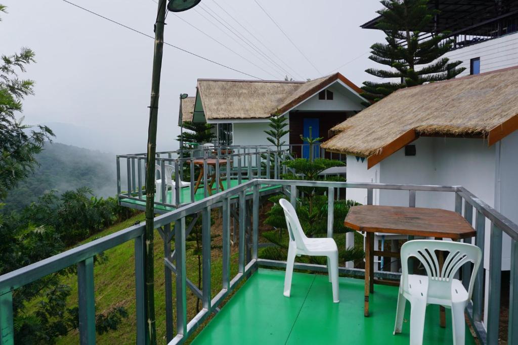 碧差汶Baan Chomdao Phu Thap Buek的阳台配有两把椅子和一张桌子,还有一间房子