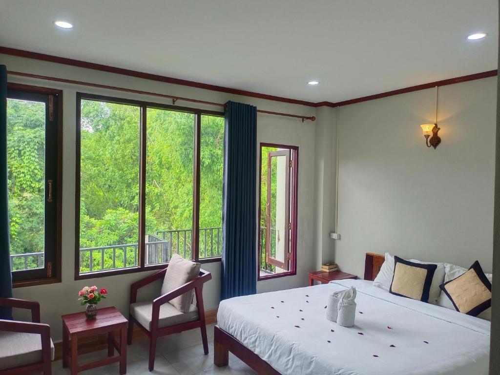 万荣Dokchampa Hotel的一间卧室配有一张床、两把椅子和窗户