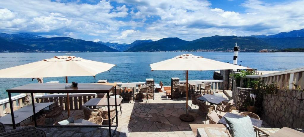 蒂瓦特Luxury Sea Residence by Kristina的水边带桌子和遮阳伞的天井