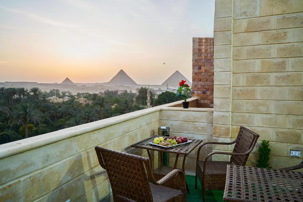 开罗New Gardenia Pyramids view的一个带金字塔的阳台的桌椅