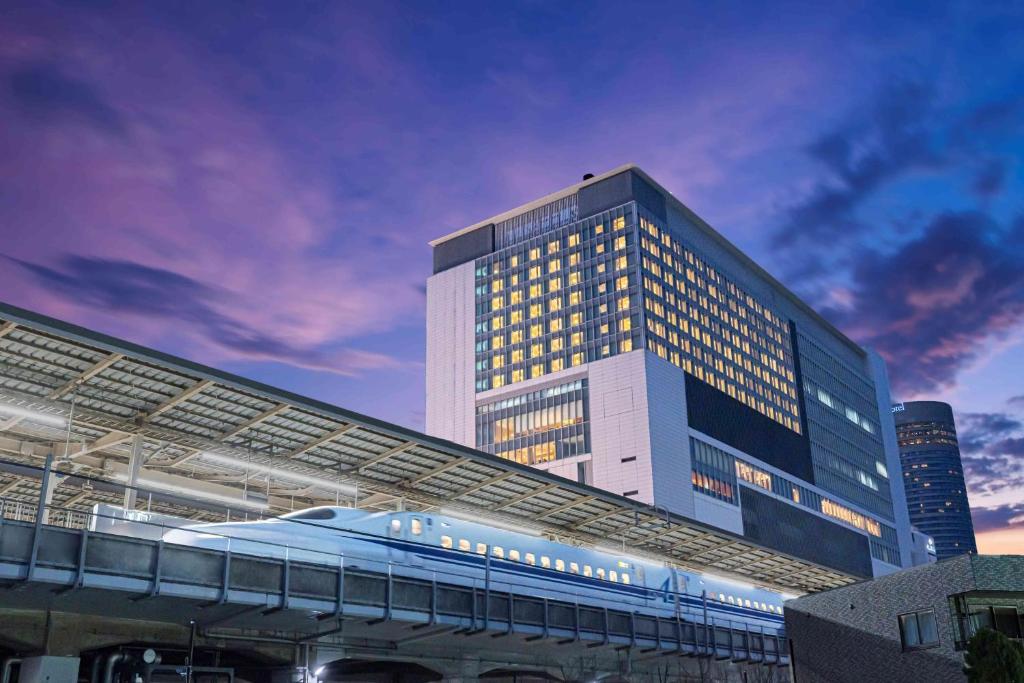 横滨阿索西亚新横滨酒店(Hotel Associa Shin-Yokohama)的前面有火车的建筑