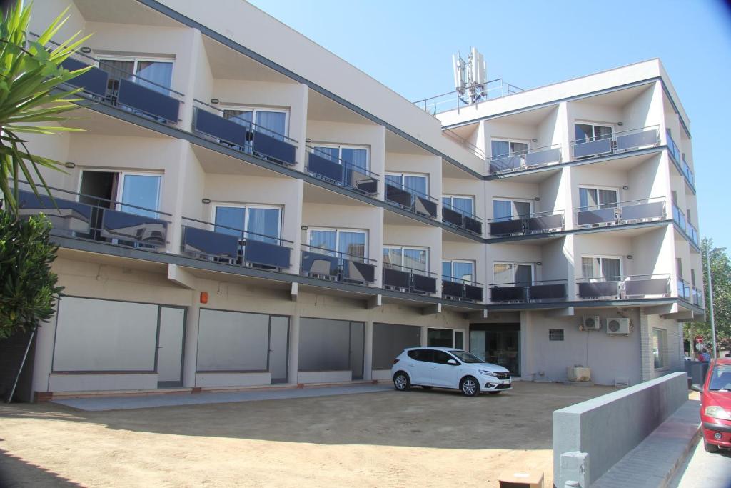 罗萨斯Aparthotel Els Molins的停车场内有停车位的公寓楼