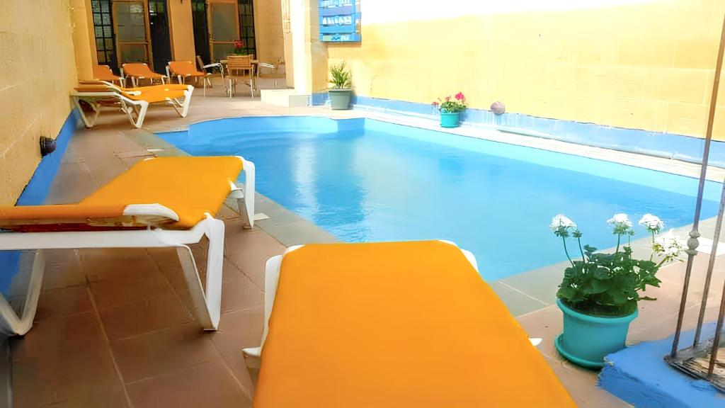 加拉3 bedrooms villa with sea view private pool and enclosed garden at Iz Zebbug的游泳池旁设有两个黄色长椅