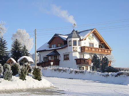 MarkneukirchenHotel Alpenhof的一座大白房子,地面上积雪