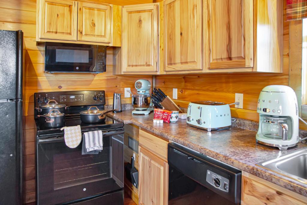 加特林堡Cabin In The Smokeys的厨房配有木质橱柜和黑色炉灶烤箱